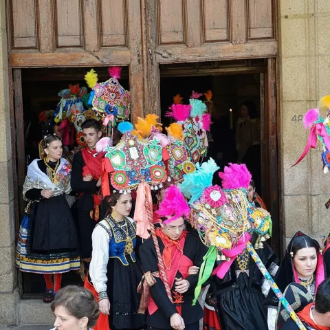 Participantes con trajes tradicionales saliendo de edificio histórico.