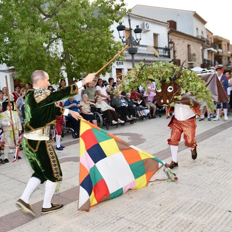 Escena festiva con danza y máscara frente al público