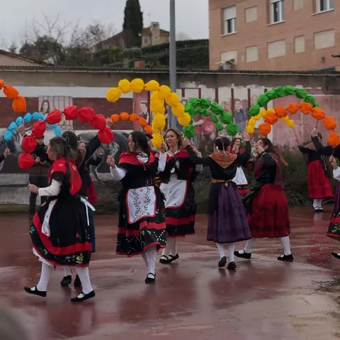 Baile tradicional con arcos de colores en plaza.