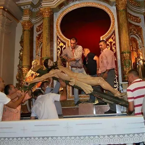 Varias personas trasladan una imagen religiosa en el altar de una iglesia.