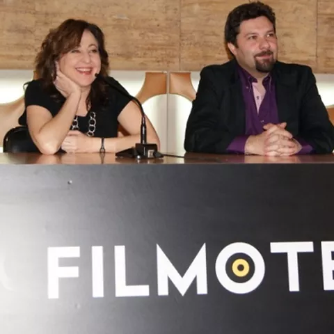 Persona sentada tras una mesa durante una presentación o charla pública.