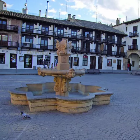 Fuente de piedra en plaza porticada