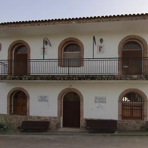 Edificio municipal blanco con balcón corrido y arcos de ladrillo