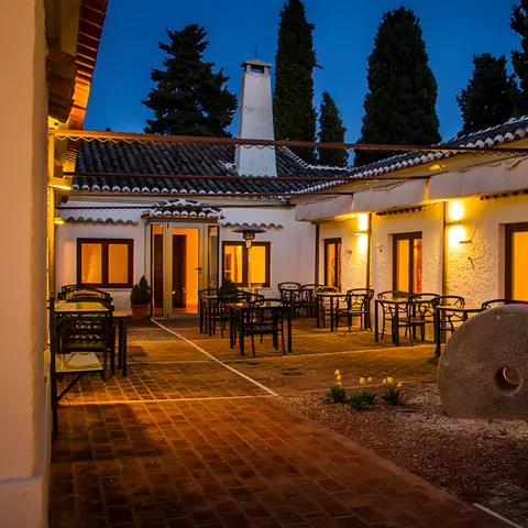 Patio iluminado al atardecer con mesas y decoración rústica