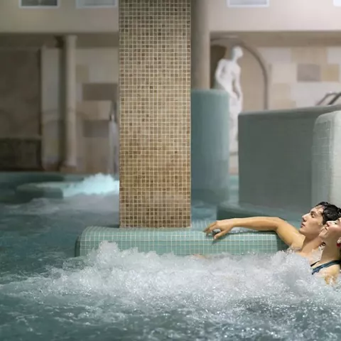 Pareja relajándose en piscina de hidromasaje interior.