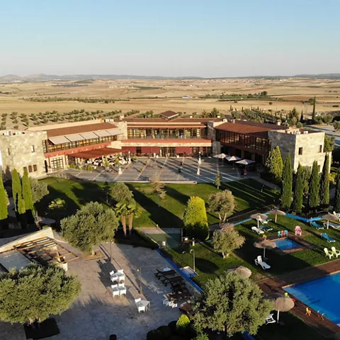 Vista aérea de un complejo rural con jardines, piscina y edificios rodeados de campos abiertos.