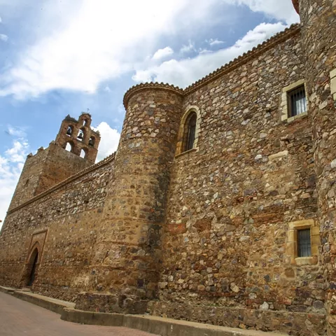 Fachada de piedra de un edificio histórico con torre y pequeñas ventanas