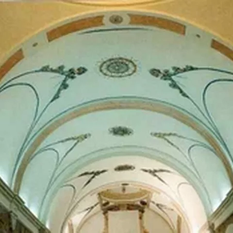Bóveda interior con arcos decorados y motivos pintados en tonos claros.
