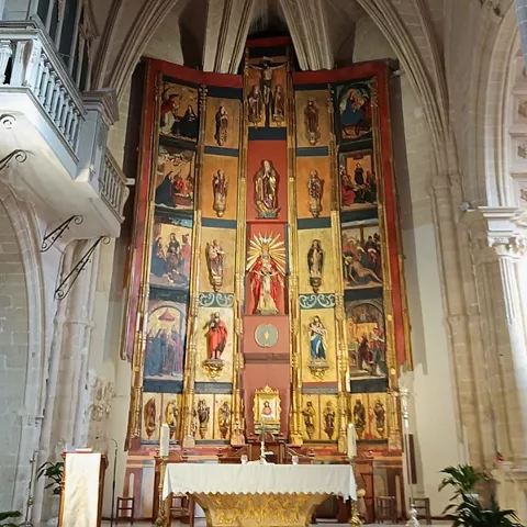 Retablo principal con paneles pintados y figuras religiosas doradas.