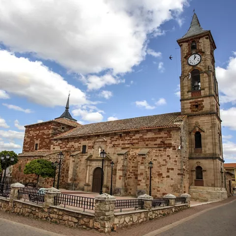 Iglesia de piedra con torre del reloj en un pueblo.