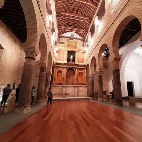 Nave interior con arquerías de ladrillo y retablo al fondo.