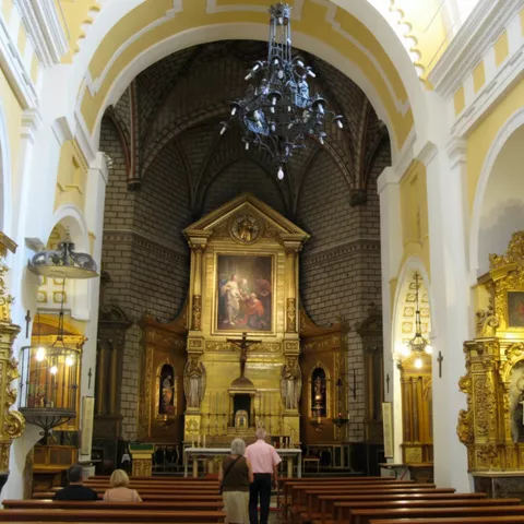 Altar mayor con retablos dorados y lámpara colgante.