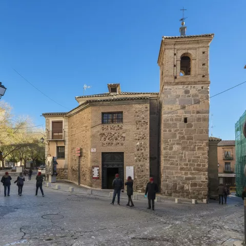 Fachada de iglesia de ladrillo y piedra en calle histórica.