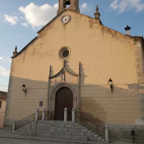 Fachada de iglesia de piedra con campanario y reloj sobre la portada.