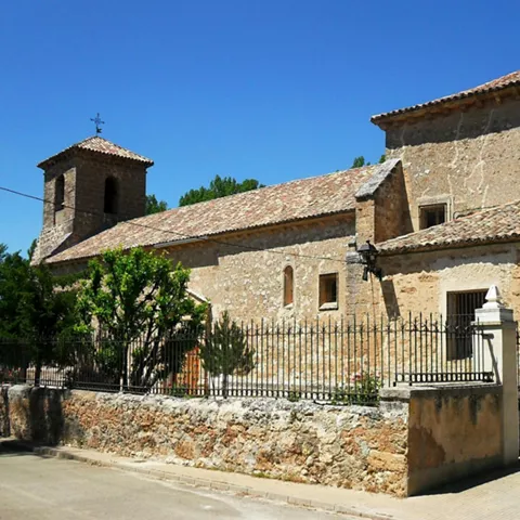 Fachada lateral de iglesia de piedra con campanario.