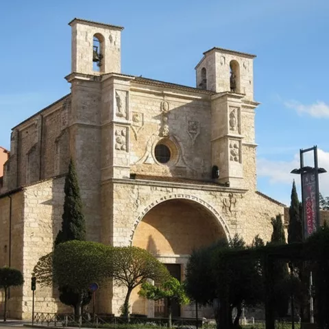 Iglesia histórica vista desde calle con árboles.