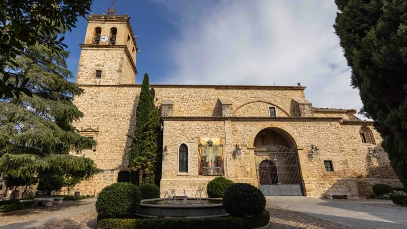Fachada de edificio histórico de piedra con torre y fuente