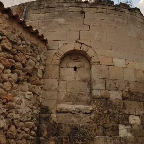 Detalle de ábside románico junto a calle empedrada.