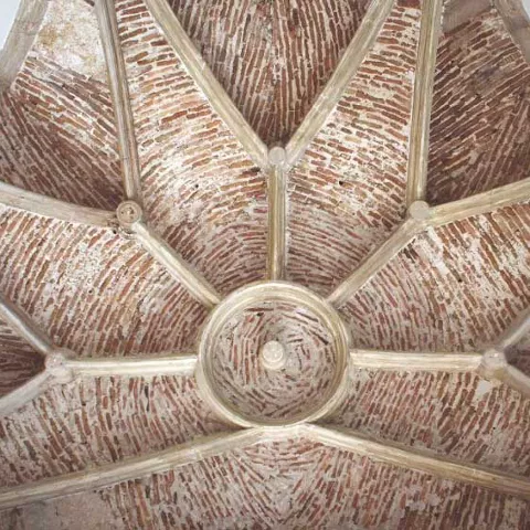 Bóveda nervada de ladrillo visto en el techo.