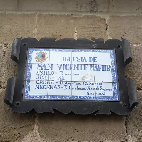 Placa cerámica informativa sobre muro de piedra.