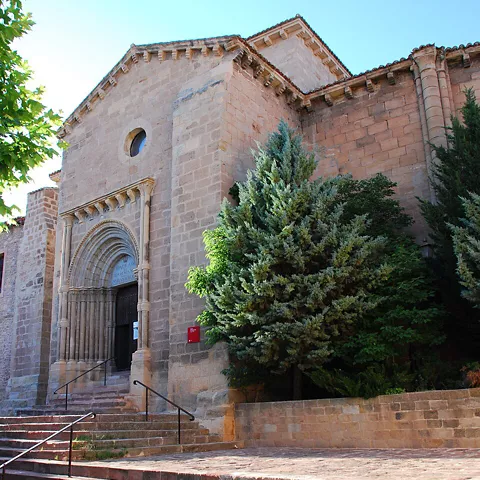 Iglesia de piedra con escalinata y arcos.