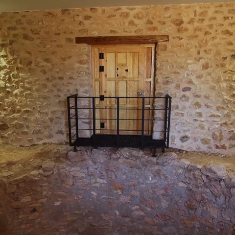 Puerta de madera sobre pasarela interior de construcción de piedra