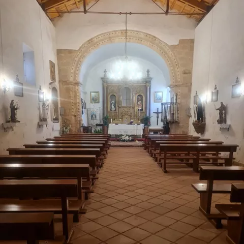 Interior con bancos de madera y altar al fondo.