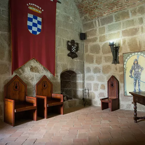 Sala interior con muros de piedra y decoración medieval.