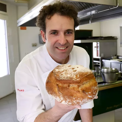 Cocinero sosteniendo un pan redondo en la cocina