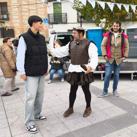 Representación callejera con varias personas sobre una plaza y público alrededor.