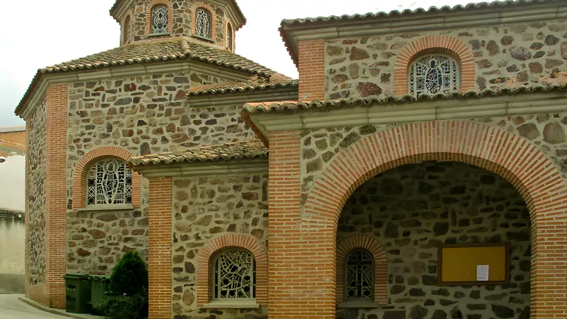 Iglesia de piedra y ladrillo con pórtico de arcos