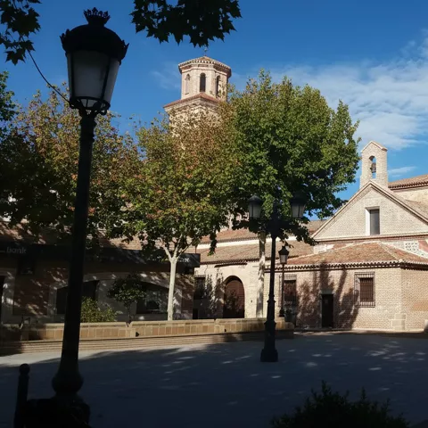 Plaza con iglesia de ladrillo y farolas
