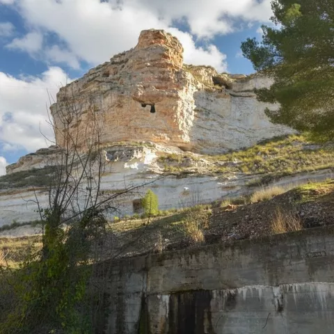 Impresionante pared de roca caliza en el entorno natural de La Recueja bajo un cielo parcialmente nublado.