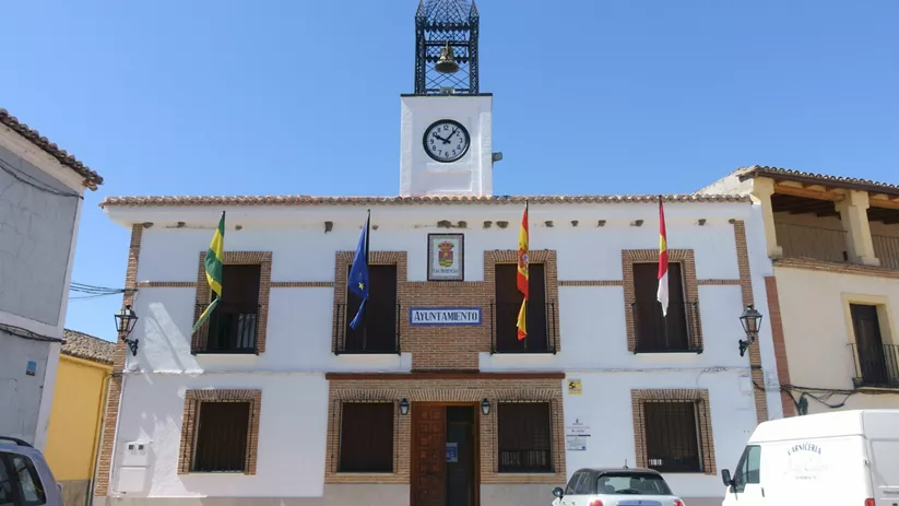 Fachada del ayuntamiento con reloj y banderas