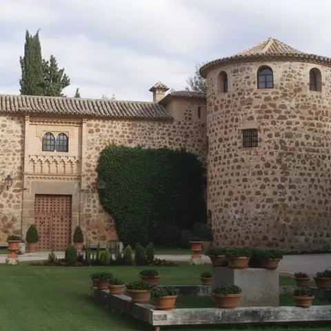 Edificio de piedra con torre circular y jardín