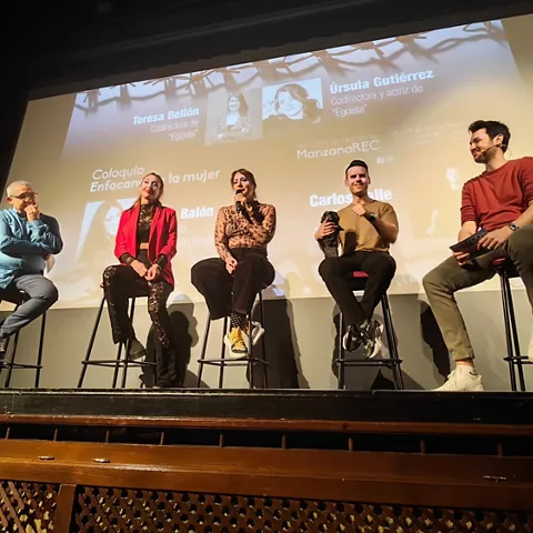 Mesa redonda con varias personas conversando sobre un escenario