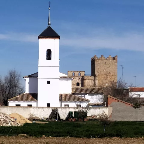 Iglesia blanca y torre de piedra entre casas bajas