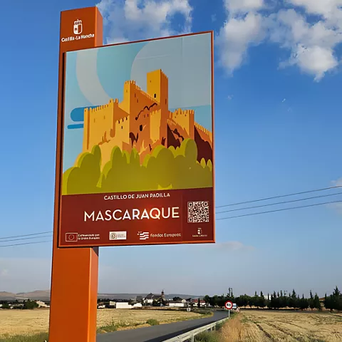Cartel turístico junto a carretera y campos secos