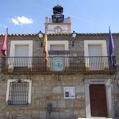 Fachada de ayuntamiento de piedra con balcón y reloj