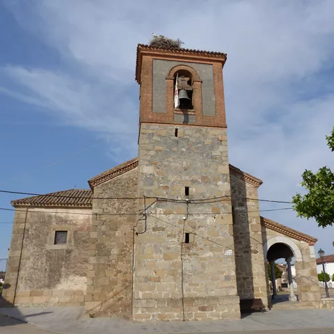 Iglesia de piedra con campanario y pórtico lateral