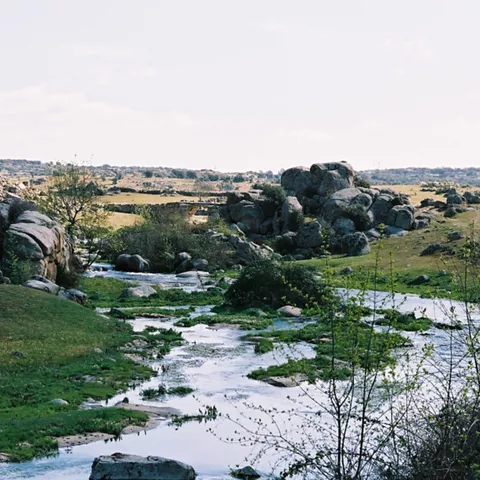 Arroyo entre rocas y pradera en paisaje rural