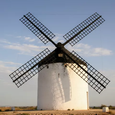 Primer plano de molino de viento con sombra de aspas sobre la fachada.