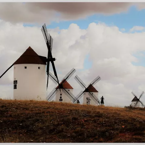 Grupo de molinos de viento sobre terreno seco con cielo parcialmente nublado.