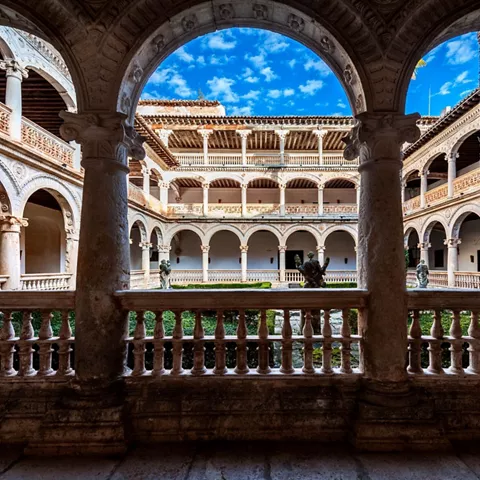 Claustro histórico con arcos de piedra y patio central ajardinado.
