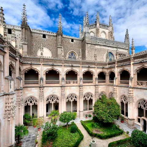 Claustro monumental de estilo gótico con jardín central.