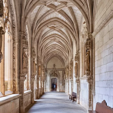 Pasillo interior con bóvedas de crucería y esculturas en las paredes.