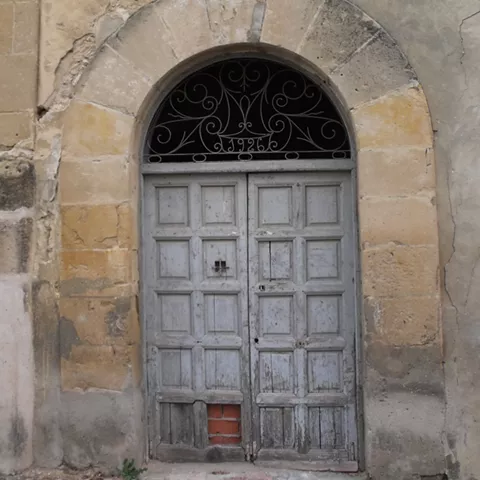 Puerta antigua de madera bajo arco de piedra.