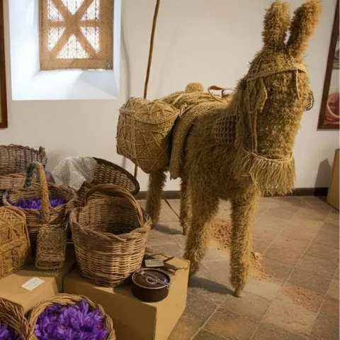 Cestas de mimbre y figura de animal de carga en sala expositiva.