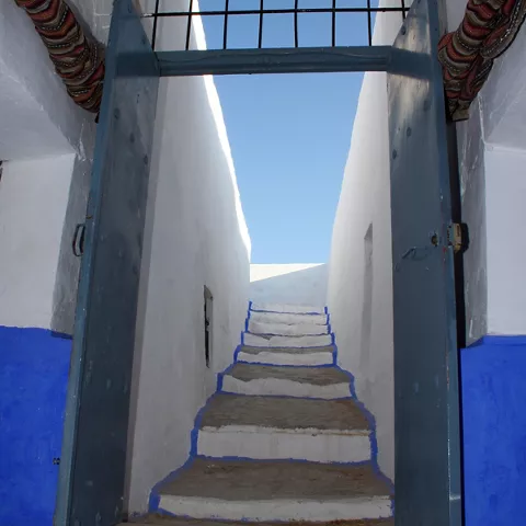 Escalera encalada con puertas azules y tragaluz