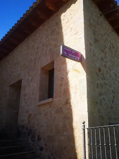 Edificio de piedra con cartel en esquina.